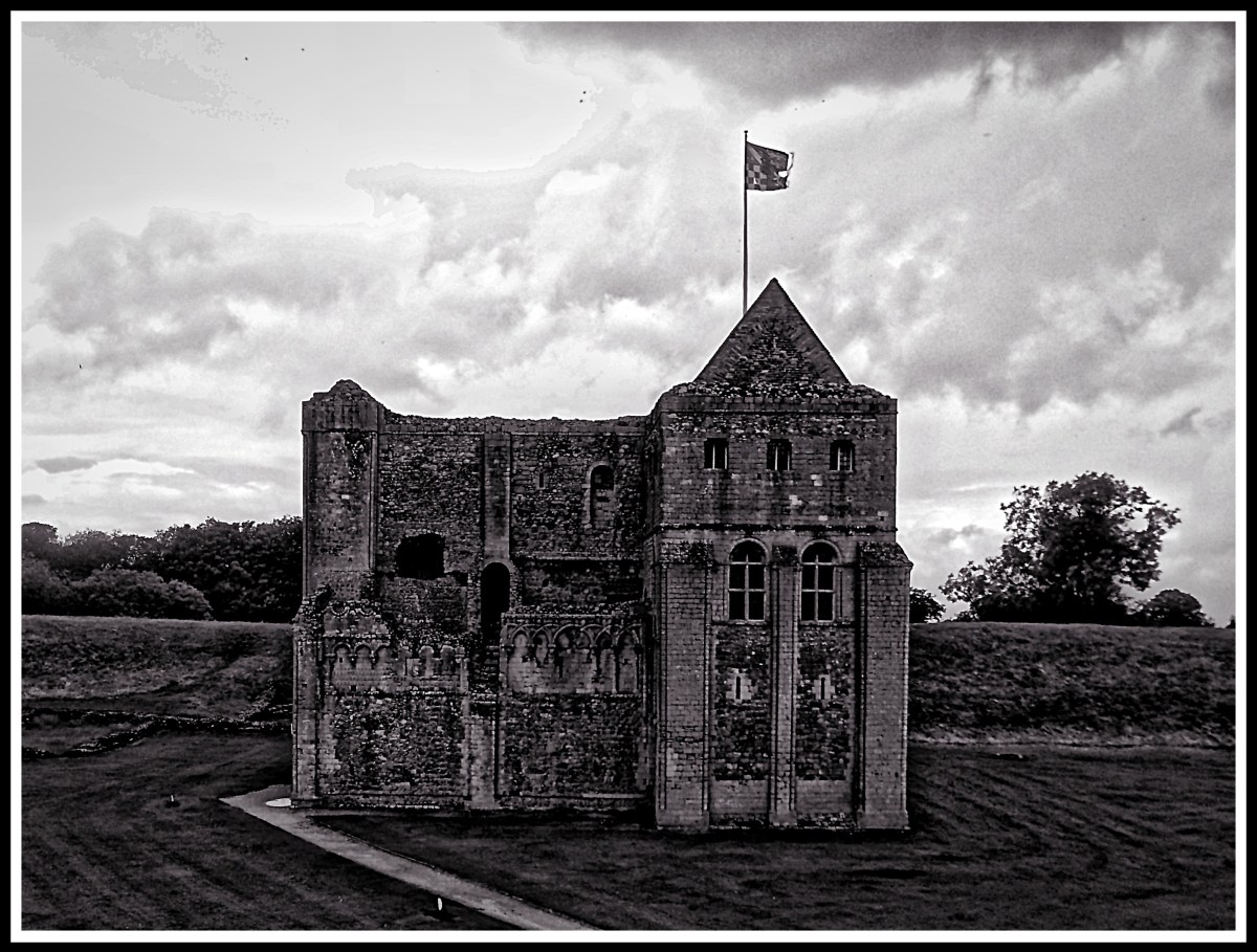 A dramatic black and white photo of castle rising castle in it's beautiful surroundings.