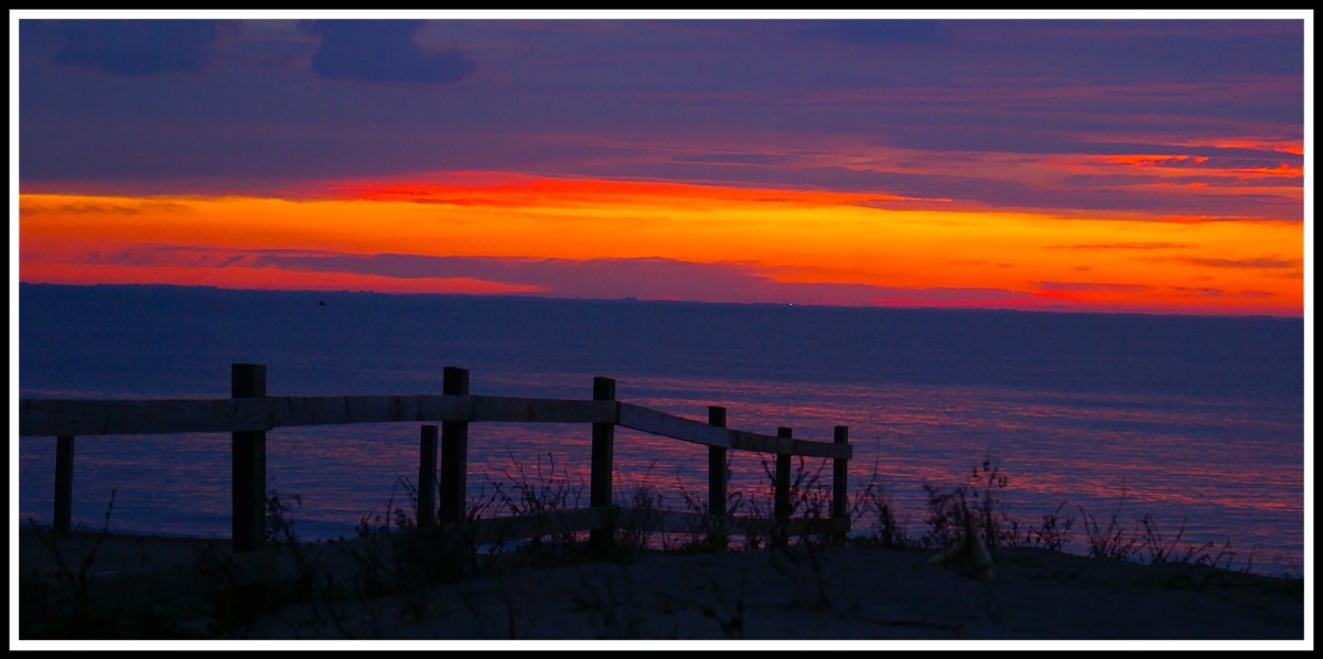 A beautiful sunset on Snettisham beach with a fence flowing down the beach from left to right