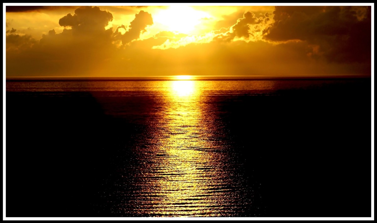 An centred orange sunset streaming beautiful bright light across the waves towards me