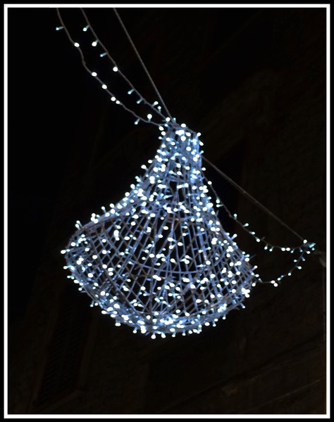 A blue light shaped as a bell hanging over the street