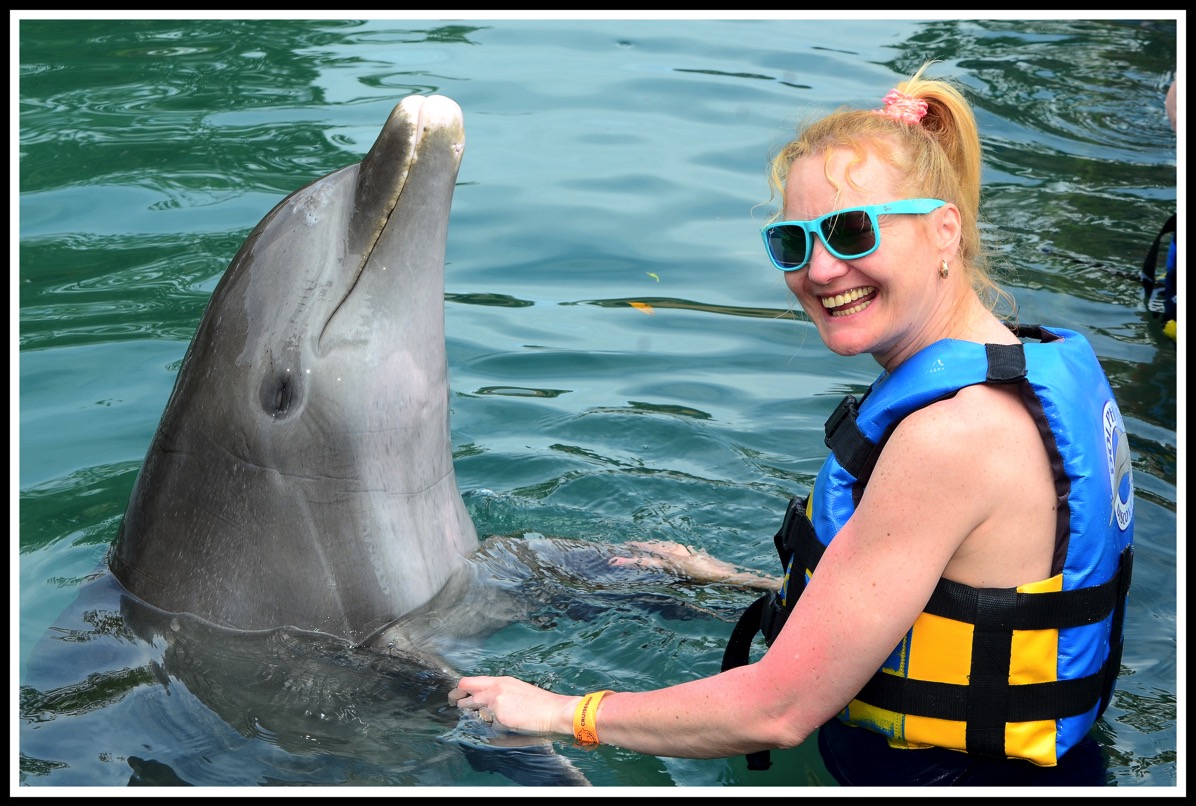 Sarah(on the right) in the water dancing with a Dolphin on her left