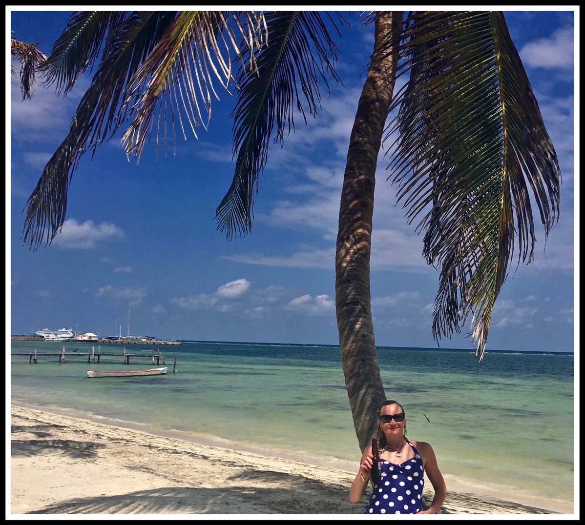 SARAH SAT AT THE BASE OF A BEAUTIFUL PALM TREE WITH THE AMAZING BLUE SEA AND YELLOW SAND LANDSCAPE BEHIND HER